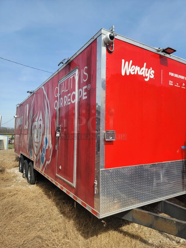 Red Wendy's mobile kitchen trailer, features brand logo and slogan. Triple axle, metallic trim, external security camera.