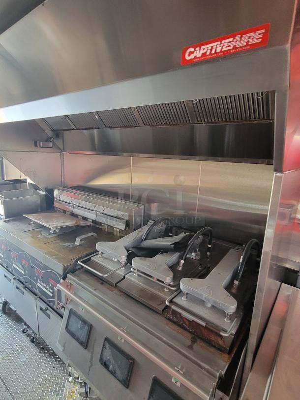 Commercial kitchen equipment with CaptiveAire hood system, featuring grills and fryers in used condition.