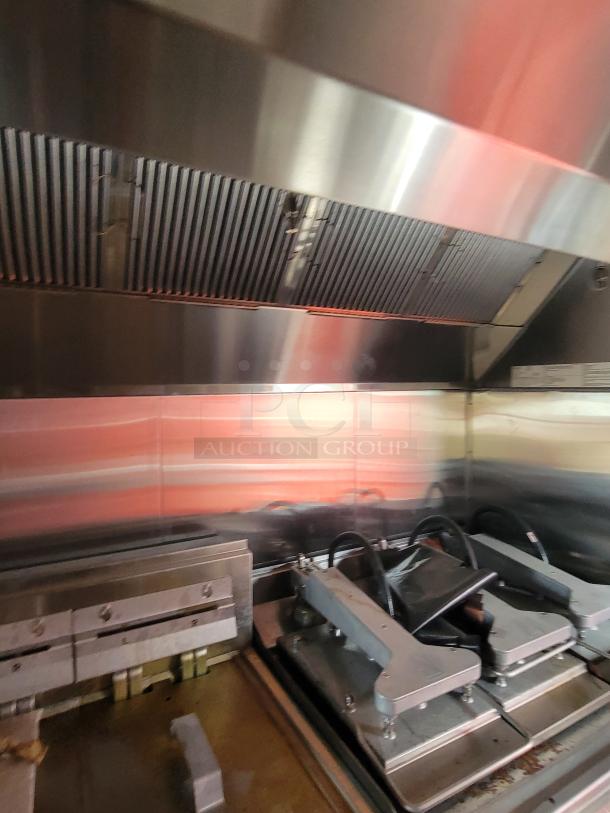 Commercial grill with dual contact presses under a stainless steel vent hood, showcasing a sleek metal finish, in good condition.