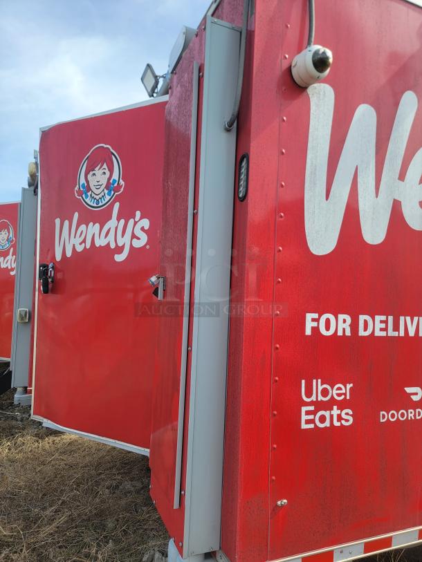 Red Wendy's delivery van with logo, featuring Uber Eats and DoorDash branding. Slightly weathered condition.