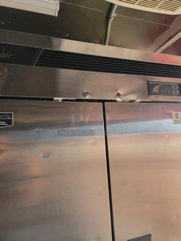 Commercial stainless steel refrigerator, top-mounted cooling unit, temperature gauge, and quality certification label visible.