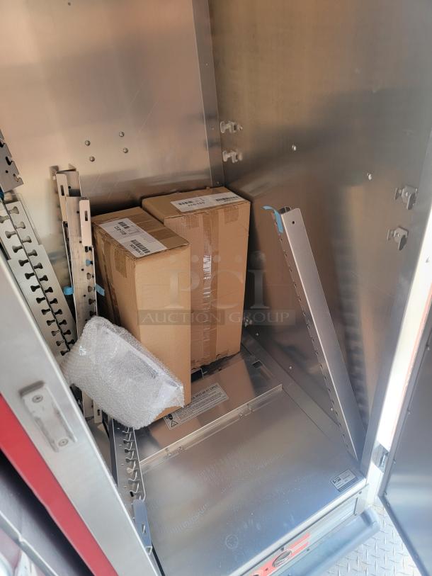 Two sealed cardboard boxes inside a metal storage compartment, with bubble wrap and packing labels visible.