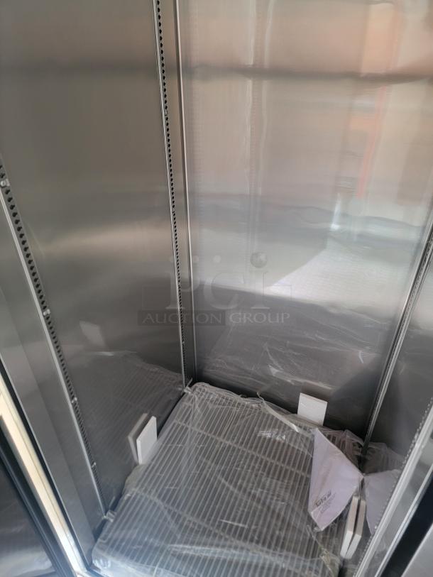 Commercial stainless steel refrigerator interior, new condition, with adjustable shelving and protective film.