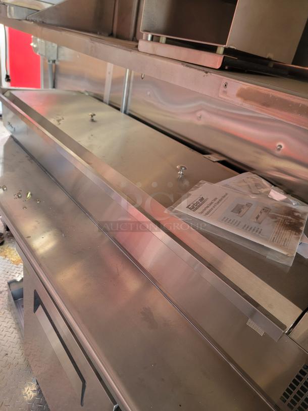 Stainless steel commercial countertop with attached shelf, in good condition. Includes equipment manual on surface.