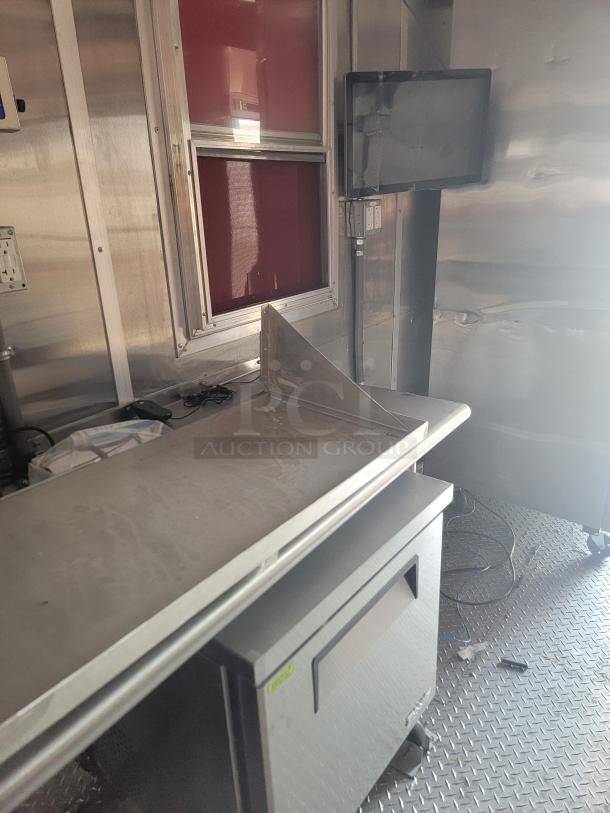 Commercial-grade stainless steel countertop with guard, mounted in a metal interior space. Includes window and electrical outlets.