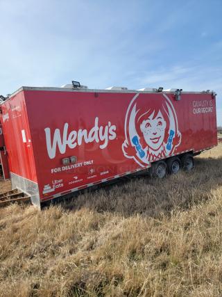 Red Wendy's delivery trailer featuring Wendy's logo, "Quality is Our Recipe" slogan, delivery service logos, and triple axles.