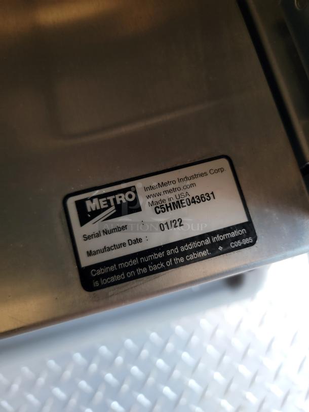 Metal cabinet with Metro label showing serial number C5HNE043631 and manufacture date 01/22. Made in USA.