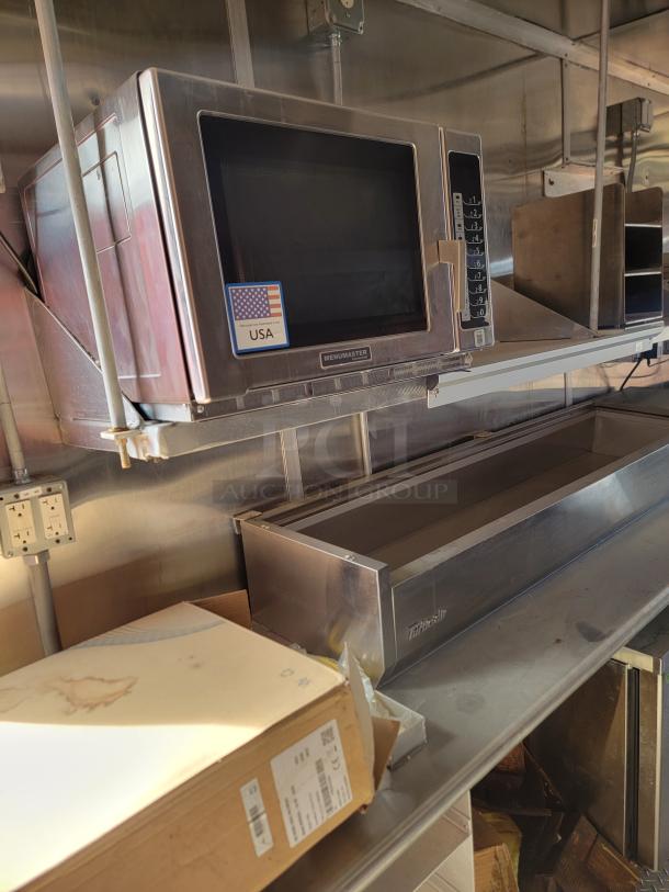 Menumaster commercial microwave, stainless steel, made in USA sticker, keypad controls, mounted on a kitchen shelf, good condition.