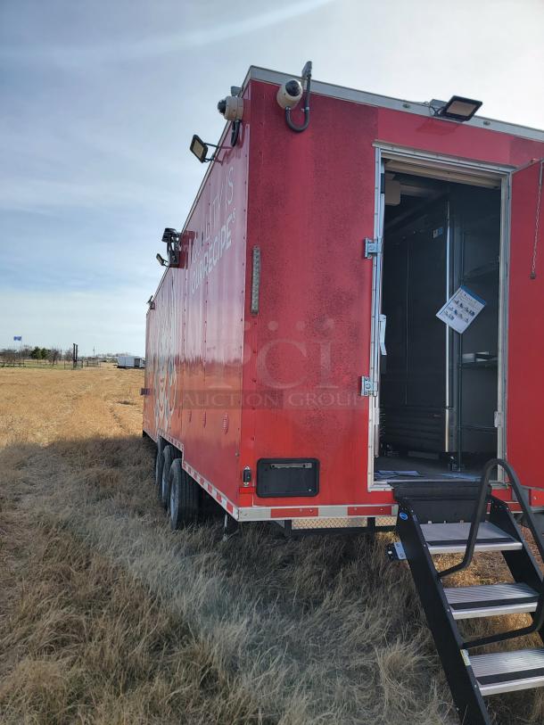 Red food trailer with security cameras, outdoor lighting, and step ladder. Open door reveals interior kitchen. Used condition.