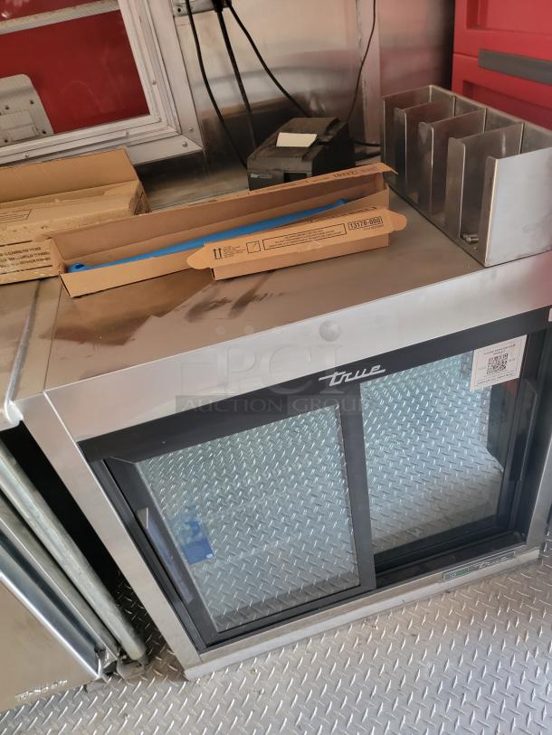 True refrigerated display case with glass door; includes packaging. Features stainless steel exterior, good condition.