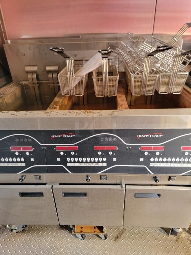 Henny Penny commercial fryer, multiple baskets, stainless steel, digital controls, used condition with visible oil stains.