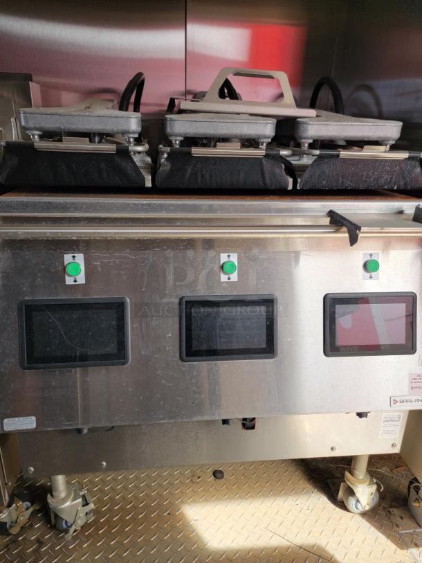 Commercial sandwich press with three grills, stainless steel body, digital controls, on wheels. Garland brand visible.