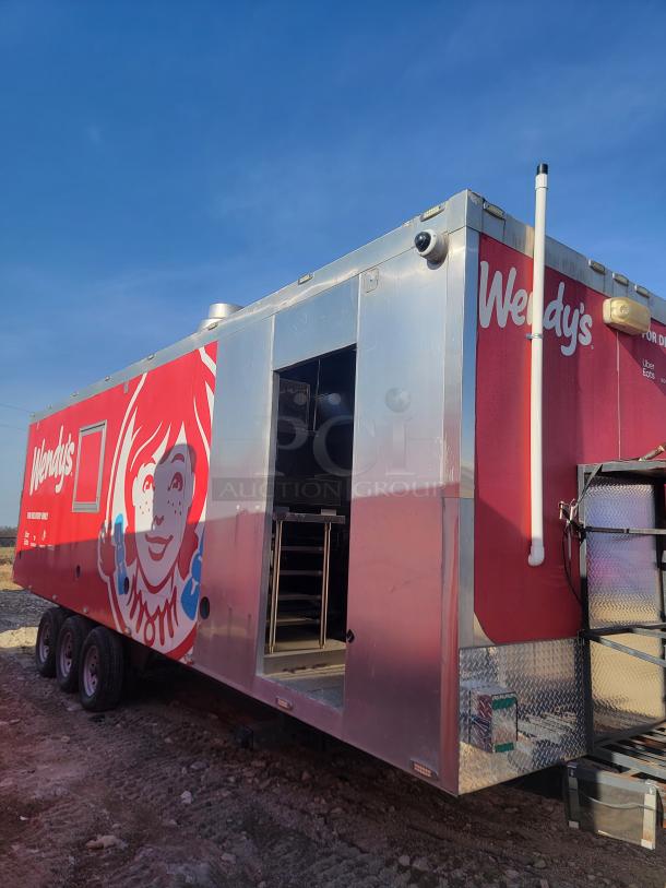 Mobile Wendy's trailer with red branding, no visible VIN, stainless steel exterior, open side door, and interior kitchen equipment.