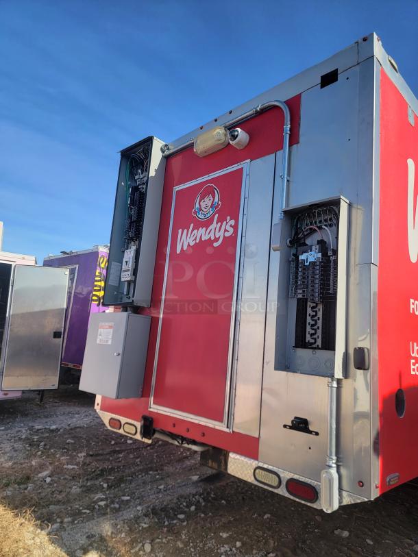 Red and silver Wendy's food truck with electrical components exposed, parked on gravel. No visible VIN.