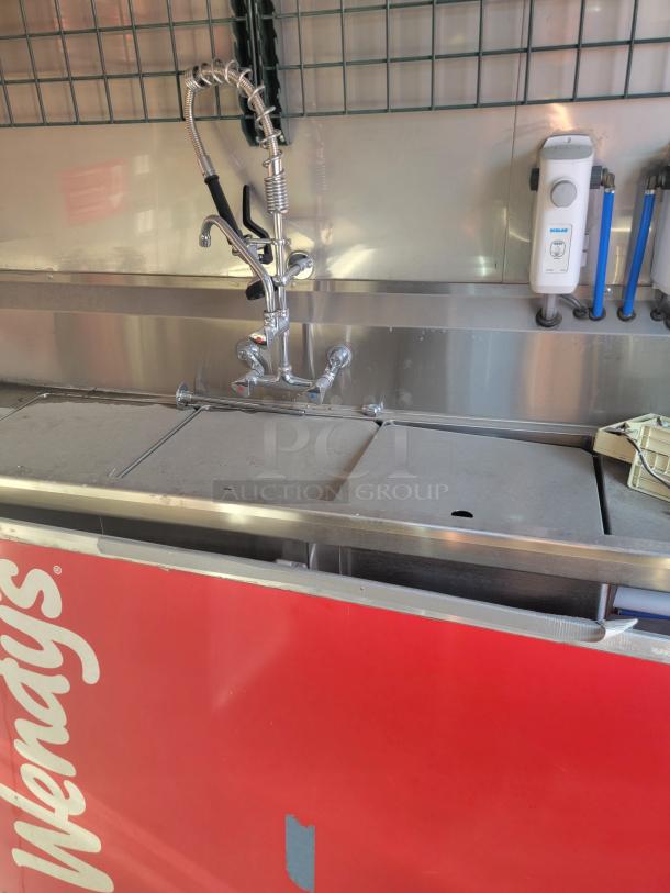 Stainless steel sink unit with dual spray faucet, Ecolab dispenser, and Wendy’s branding, in good condition.