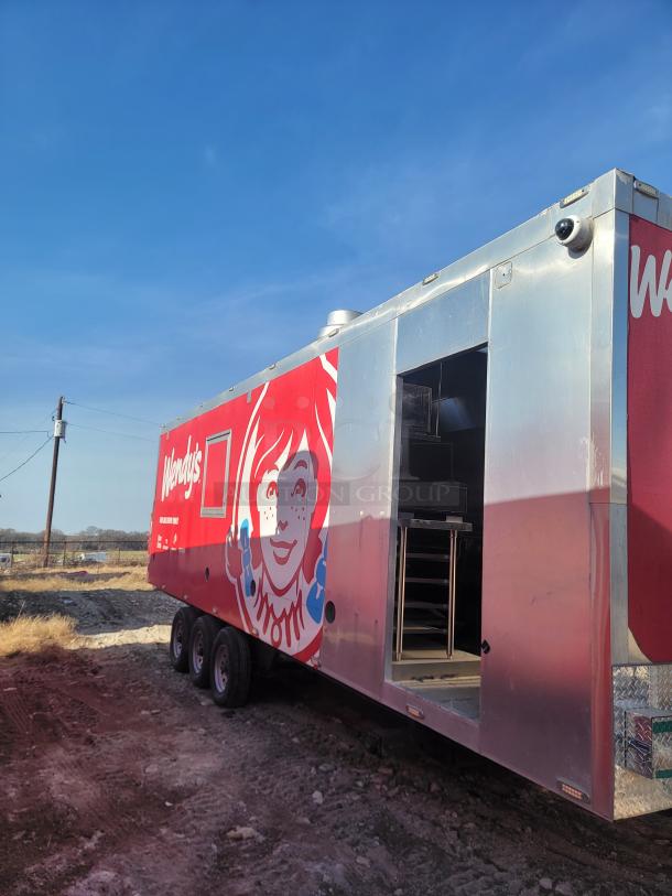 Wendy's mobile kitchen trailer with red logo, no VIN, stainless steel exterior, triple axle, missing equipment inside.