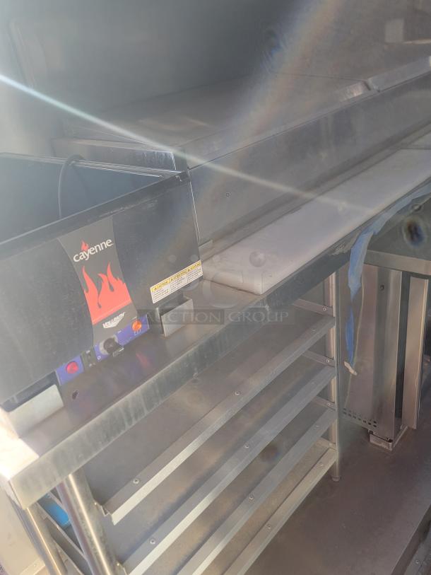 Commercial kitchen equipment featuring a Cayenne food warmer, metal shelving, and stainless steel surfaces, in good condition.