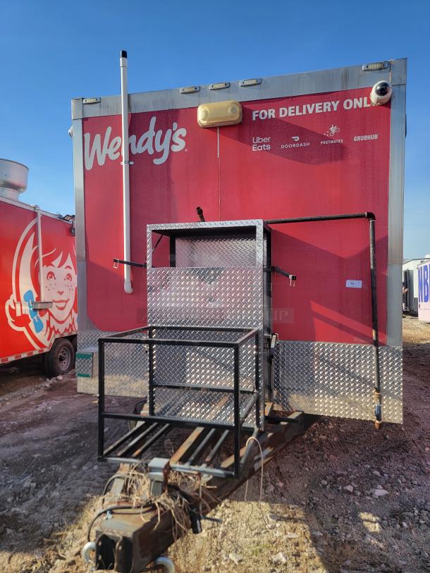 Wendy's mobile kitchen trailer with delivery service logos on red exterior. Metal frame and hitch visible. Used condition.