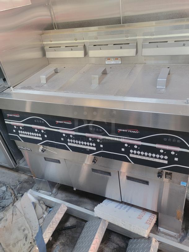 Henny Penny commercial fryer with multiple compartments, stainless steel, control panel visible, in used condition.