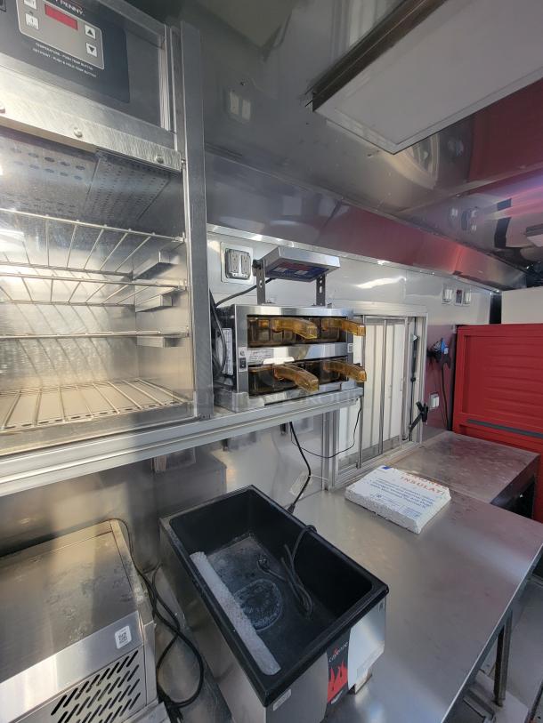 Commercial kitchen interior with stainless steel shelves, warming trays, and equipment. Clean condition, professional setup.