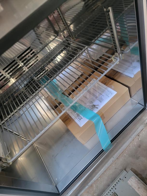Metal shelving unit with boxes, labels, and a blue strap. Condition appears new. No visible brand or model identifiers.