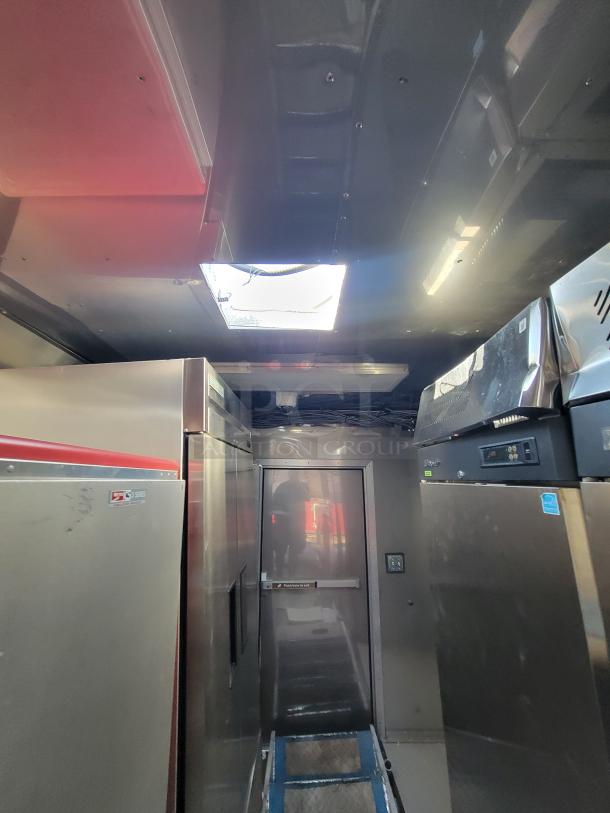 Interior view of a kitchen setup with stainless steel appliances, featuring a skylight and a visible door.