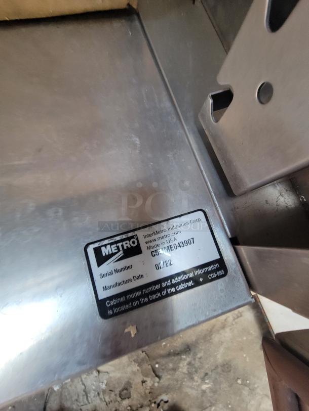 Industrial metal surface with Metro label showing serial C59-ME043907 and manufacture date 04/22. Made in USA.