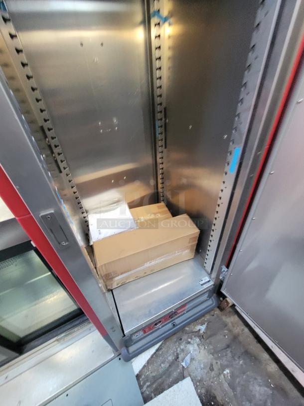 Metal storage cabinet interior with cardboard boxes on the bottom shelf, visible wear on floor. No visible labels or tags.
