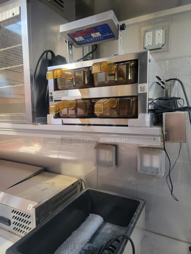 Commercial kitchen scale setup with a portion control unit and multiple amber containers. Stored in a stainless steel kitchen environment.