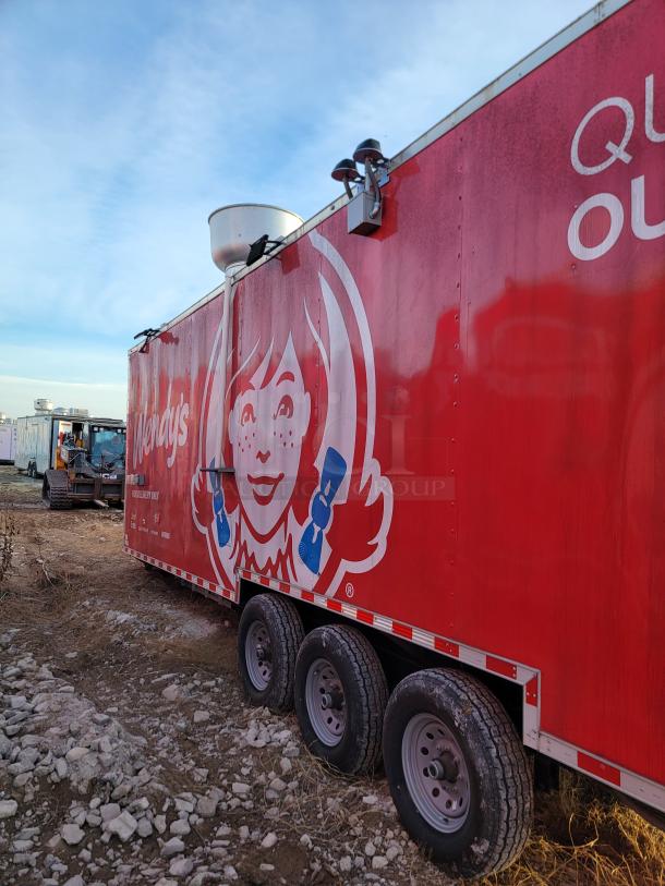 Red trailer with Wendy's logo, tri-axle, silver roof vent, outdoor condition, promotional graphics.