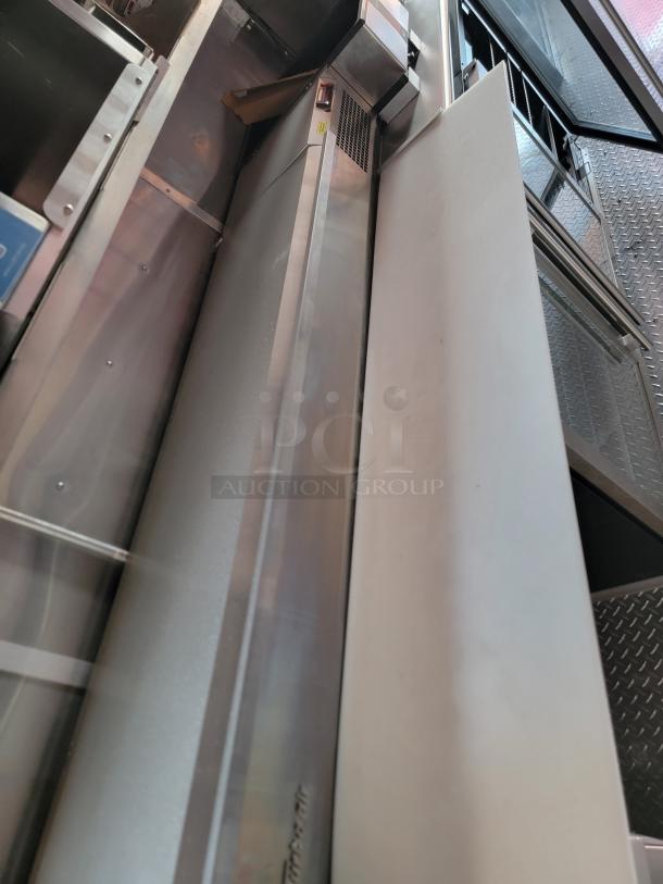 Stainless steel commercial refrigerator with side vent, light wear. Suitable for kitchen or industrial use.