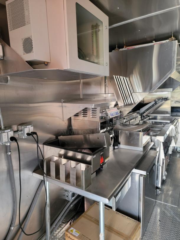 Stainless steel commercial kitchen equipment with vent hoods and partitioned countertop in excellent condition.