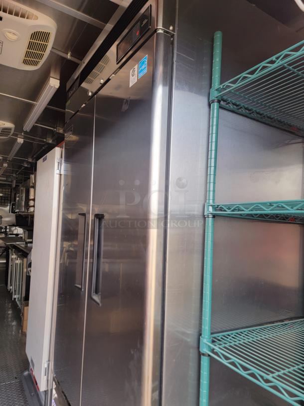 Commercial stainless steel refrigerator with double doors, temperature control panel, and certified energy labels, in used condition.