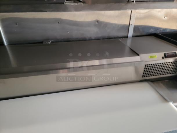 Stainless steel commercial prep table with refrigeration unit, cutting board surface, and vent panel. Good condition.