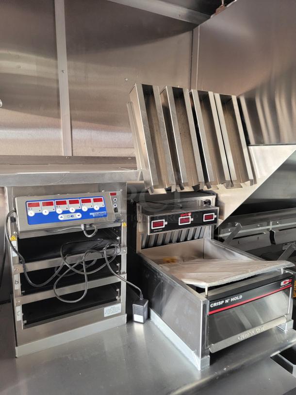 Commercial kitchen equipment featuring a Crisp N' Hold by Carter-Hoffmann, with control panel and heat lamps, in stainless steel.