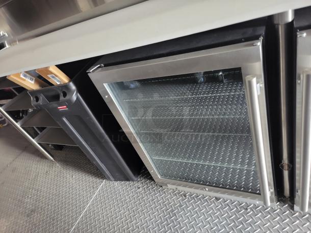 Stainless steel refrigerator with glass door, diamond plate flooring inside. Good condition, perfect for commercial use.