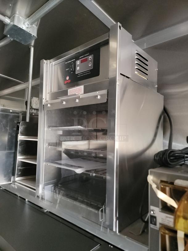 Commercial bun holding cabinet in stainless steel with electronic controls, model "Henry Penny." Visible label indicates brand name.