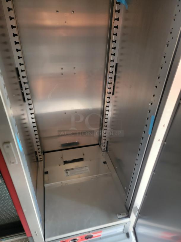 Metal storage cabinet with adjustable shelving slots, no shelves installed. Shows minor wear. Label indicates safety warnings.