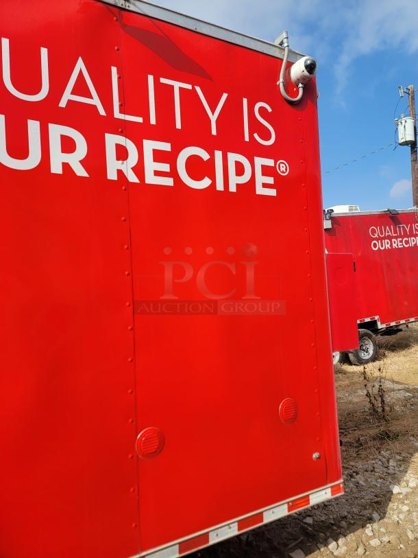 Red mobile food truck with "Quality is Our Recipe" text and a mounted security camera. In good condition, on gravel.