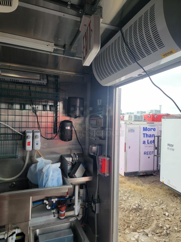 Industrial kitchen interior with Vevor air curtain, exit sign, and stainless steel sink. Equipment appears in good condition.