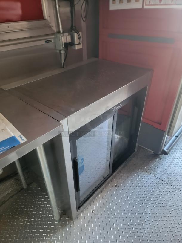 Stainless steel True commercial refrigerator with glass sliding doors, good condition, visible brand logo.