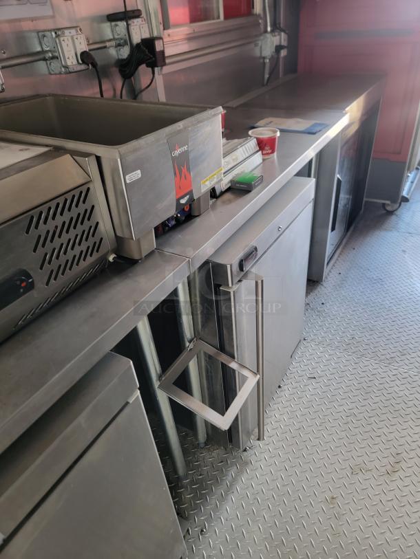 Commercial kitchen equipment with a Cayenne food warmer, stainless steel counters, and storage cabinets. Good condition.