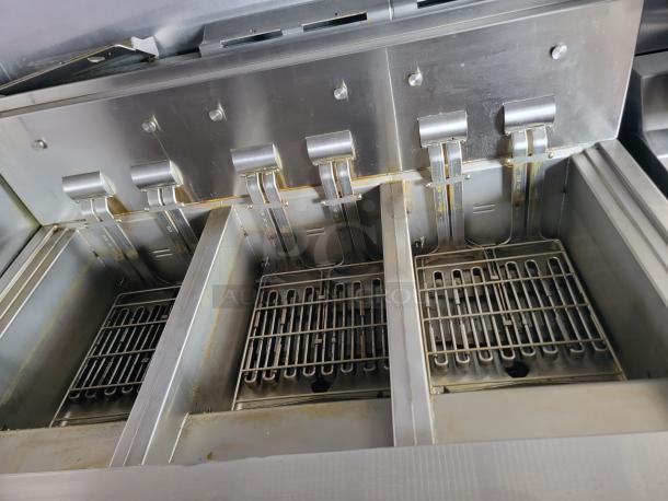 Commercial deep fryer with three compartments, stainless steel, slight wear. Includes removable grates and heating elements.