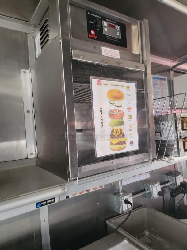 Commercial stainless steel food holding cabinet branded Wendy's, with a build card for a Texas Double Cheeseburger displayed. The cabinet features digital controls and is mounted in a commercial kitchen setting.