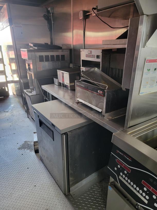 Commercial kitchen equipment, including a Henny Penny fryer and Crisp N Hold warmer. Stainless steel surfaces, fair condition.