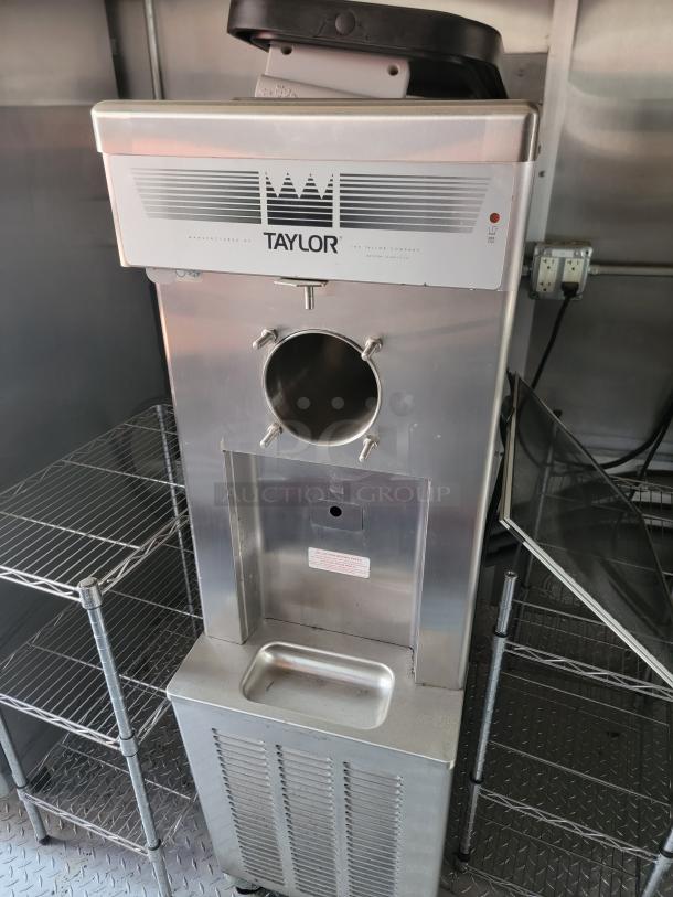 Taylor ice cream machine, stainless steel, commercial model. Features front dispensing spout and brand markings. Used condition.