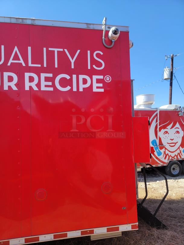 Red food truck with "QUALITY IS OUR RECIPE" slogan and a graphic of a girl's face. Equipped with security cameras.