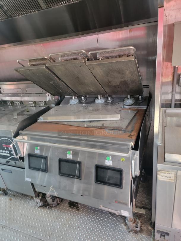 Commercial kitchen grill with adjustable iron plates, stainless steel body, visible wear and rust. Features digital controls.