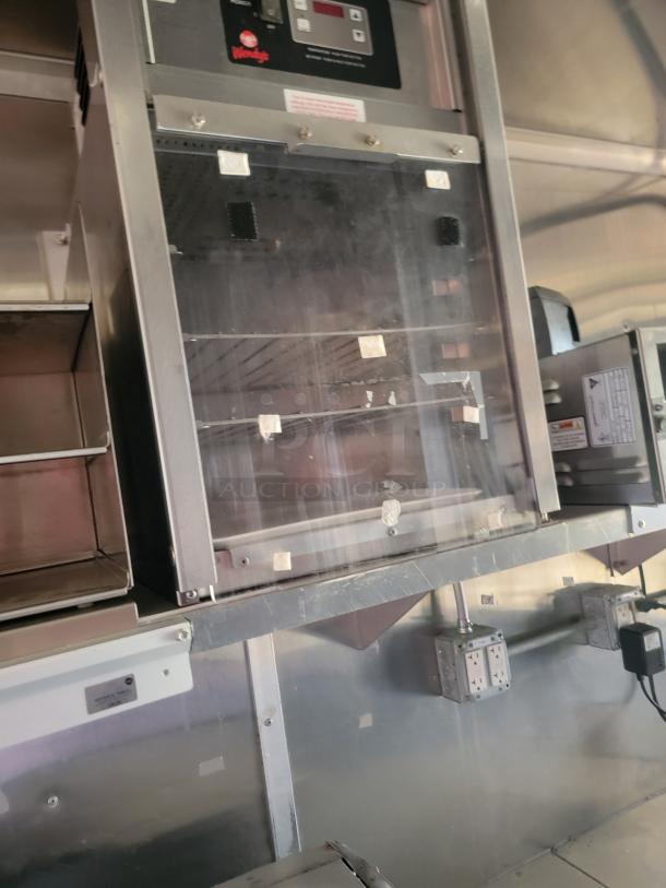Commercial food warmer with Wendy's branding, stainless steel, transparent front, digital controls, and visible interior racks.