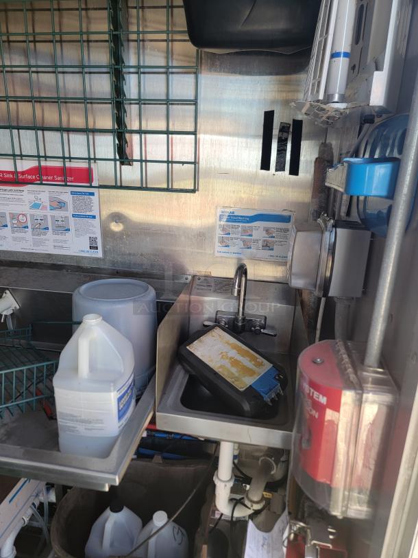 Commercial kitchen sink setup with faucet, sanitizer container, and Ecolab handwashing guide. Stainless steel construction, good condition.